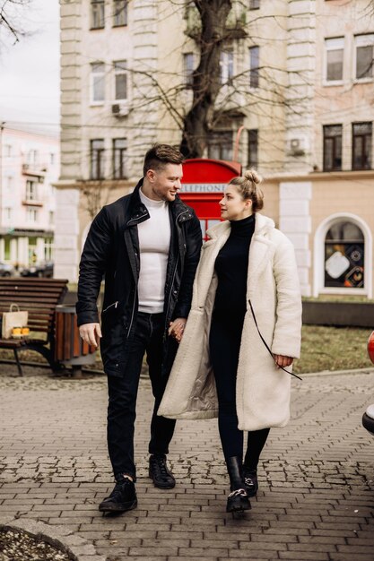 Um lindo casal apaixonado em agasalhos está andando na rua na primavera Recreação juntos ao ar livre Jovem casal estiloso