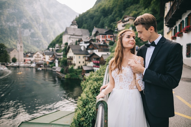 Um lindo casal de noivos caminha perto de um lago em uma cidade fada austríaca, Hallstatt.