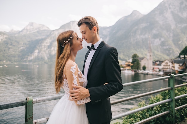 Um lindo casal de noivos caminha perto de um lago em uma cidade fada austríaca, hallstatt.