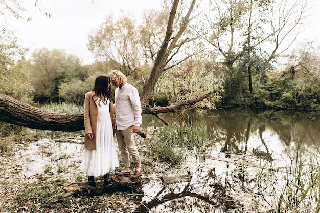 Um lindo casal no estilo boo abraça sentado em um galho sobre o lago