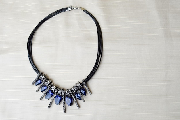 Um lindo colar feminino elegante em um elástico preto com diamantes azuis brilhantes