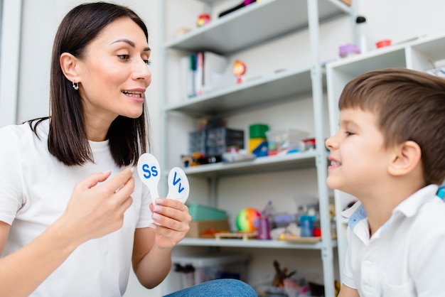 Um lindo menino com um fonoaudiólogo é ensinado a pronunciar as letras, palavras e sons.