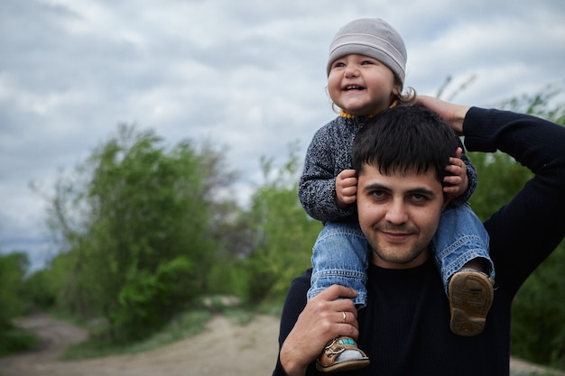 Um lindo menino loiro de olhos azuis brinca com seu pai em um campo ao ar livre, dia dos pais