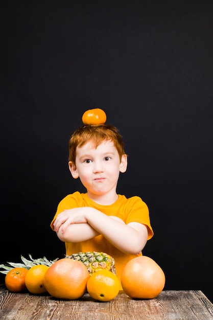 Um lindo menino ruivo com frutas cítricas