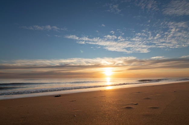 Um lindo pôr do sol na praia de Mazagon Espanha Ao fundo as silhuetas de dois surfistas