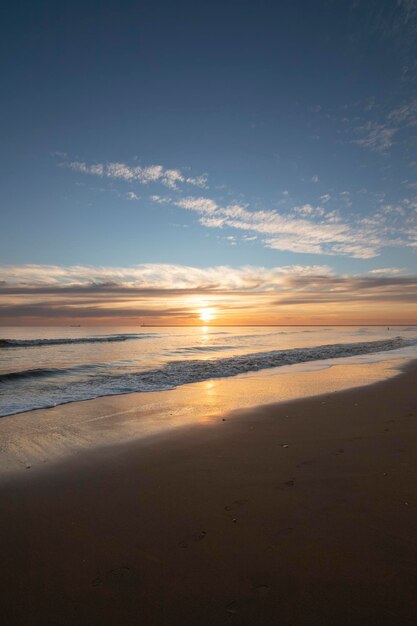 Um lindo pôr do sol na praia de Mazagon Espanha Ao fundo as silhuetas de dois surfistas