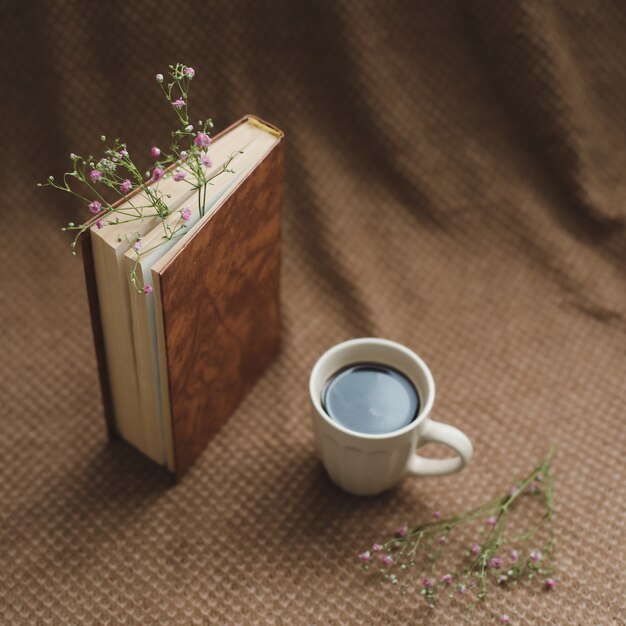 Um livro com flores e uma xícara de café