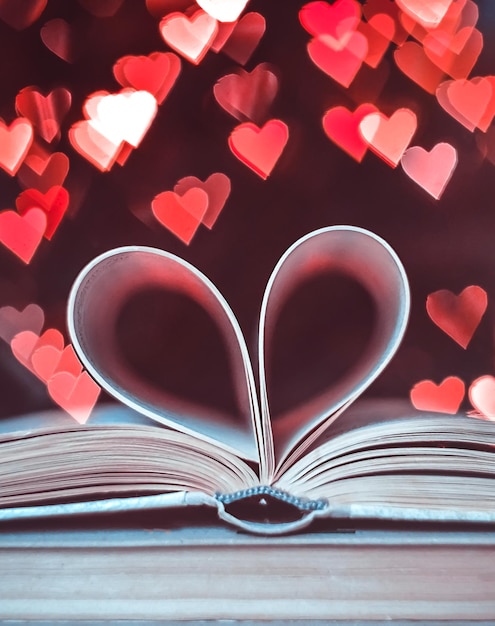 Um livro de papel em forma de coração contra um fundo de bokeh NA FORMA DE CORAÇÕES Valentine