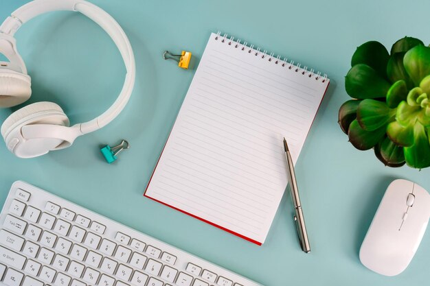 Um local de trabalho em uma mesa de escritório em casa com um teclado de flores e um caderno em um layout plano