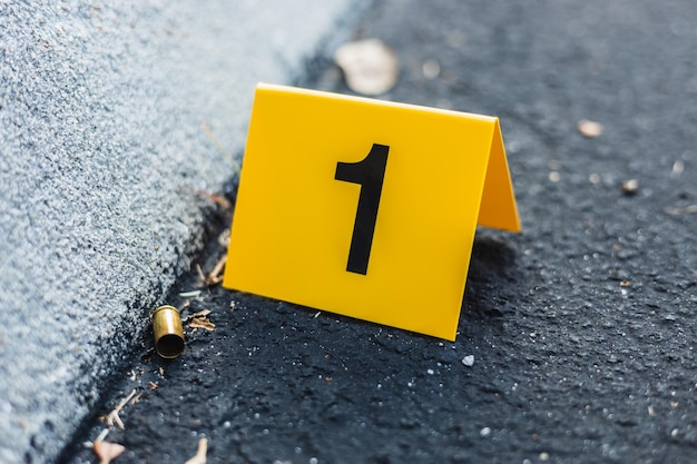 Um marcador amarelo de evidências da cena do crime na rua depois de uma arma de tiro de bala de bronze com cartucho de pistola de 9mm
