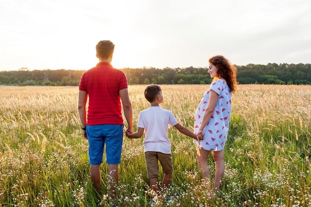 Um marido, sua esposa e um filho estão posando no campo de trigo ao pôr do sol