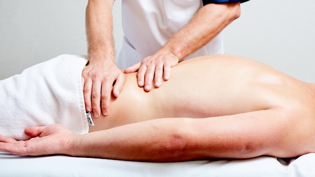 Um massagista faz um homem massagear a saúde do tratamento de spa