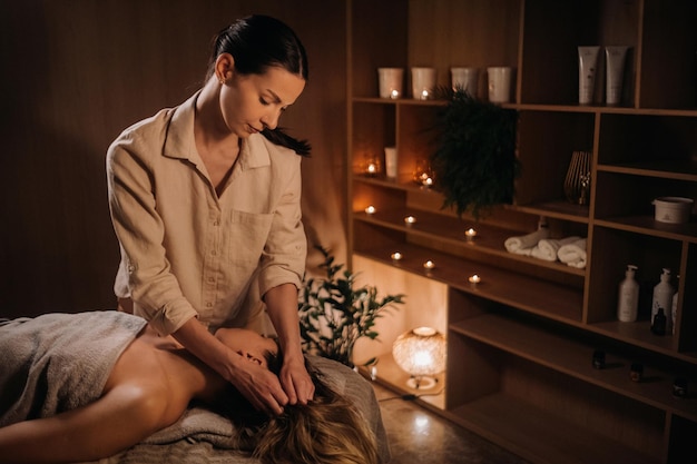 Um massagista faz uma massagem corporal a uma mulher em um centro de spa um massagista profissional massageia o ombro de uma garota deitada em um centro de spa