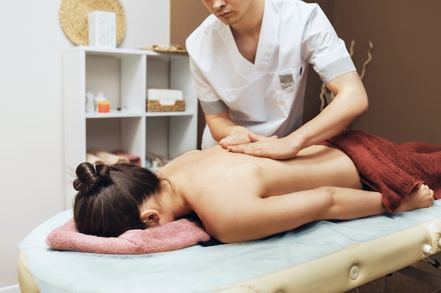 Um massoterapeuta profissional realiza uma massagem nas costas para uma cliente em seu consultório, terapia manual da coluna vertebral