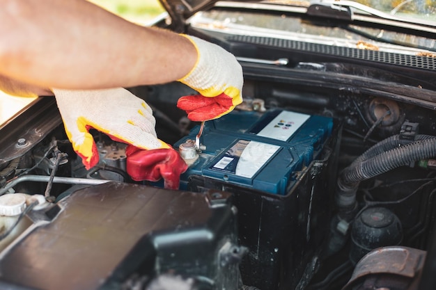 Foto um mecânico de automóveis está consertando um carro removendo a bateria