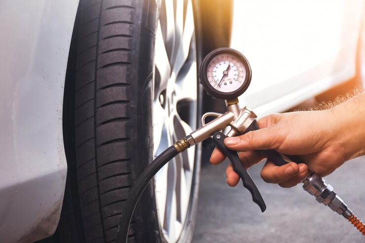 Um mecânico de automóveis infla um pneu com uma arma de inflação de pneus de ar