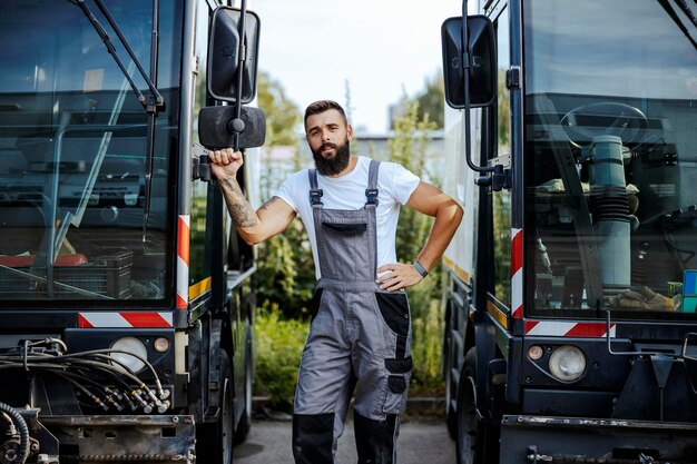 Um mecânico de automóveis trabalhador em pé ao ar livre e apoiado no ônibus