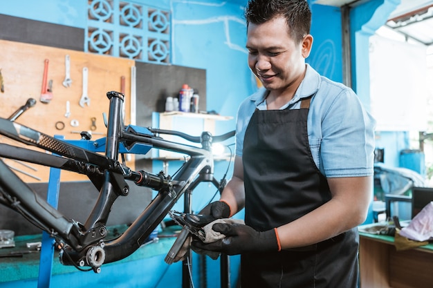 Um mecânico de bicicletas de avental segura a manivela enquanto a instala em uma bicicleta nova