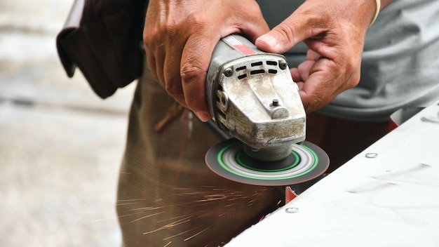 Um mecânico está cortando chapas metálicas usando uma moagem de roda elétrica na oficina