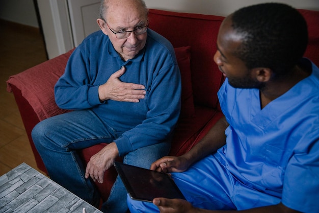 Um médico afro-americano conversando com seu paciente idoso cujo peito dói