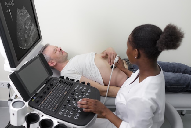 Foto um médico afro-americano examina um paciente do sexo masculino com uma máquina de ultrassom