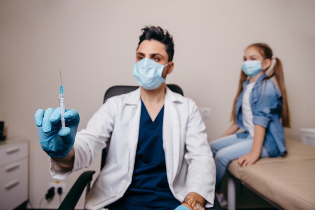 Um médico árabe ou turco se prepara para ser vacinado contra o coronavírus. Menina no fundo. Foto de alta qualidade