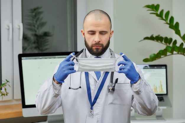 Um médico caucasiano, colocando uma máscara facial em seu escritório.