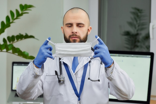 Um médico colocando uma máscara protetora em seu escritório.