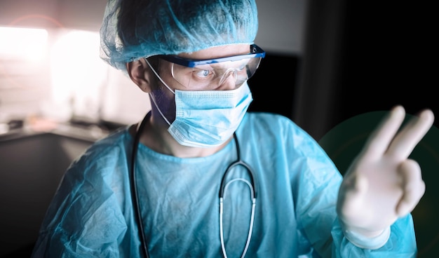 um médico de uniforme e uma máscara com óculos trabalha em um hospital tarde da noite