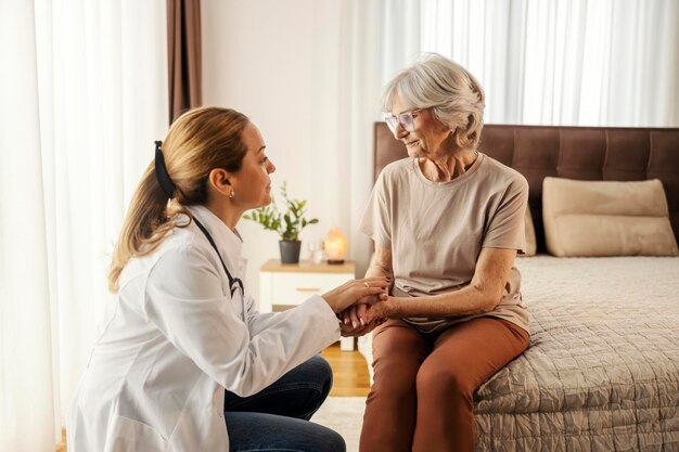 Um médico está confortando uma mulher idosa triste em casa durante sua visita