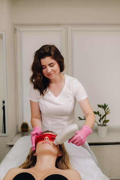 Um médico faz depilação a laser para um cliente de pêlos faciais indesejados em um salão de beleza