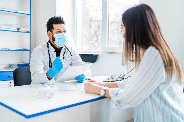 Foto um médico indiano consulta seu paciente, ele está com uma máscara de proteção e luvas