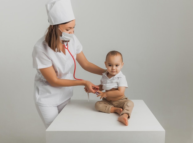 Um médico infantil examina um menino de um ano com um estetoscópio em um hospital. conceito de saúde