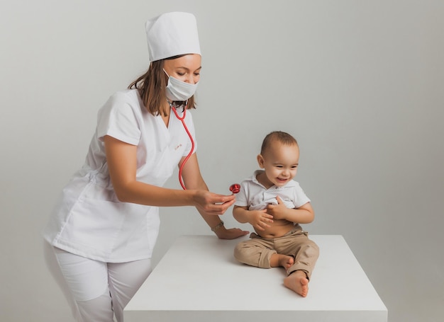 Um médico infantil examina um menino de um ano com um estetoscópio em um hospital. conceito de saúde