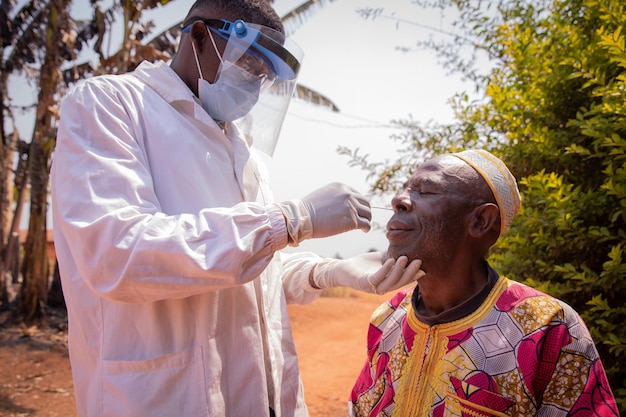 Foto um médico realiza um teste de coronavírus com um cotonete em um paciente africano idoso teste covid19 na áfrica