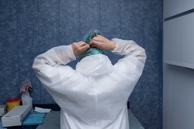 Foto um médico se prepara para atender um paciente. a mulher prepara (trajes de proteção, googles, luvas e máscaras) todas as proteções necessárias para se proteger de cobiça-19