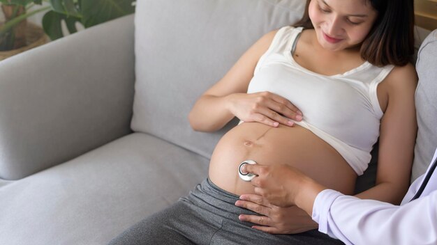 Um médico segurando estetoscópio está examinando uma mulher grávida no hospital