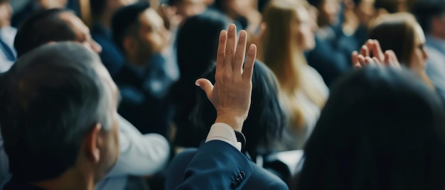 Um membro da audiência envolvido levanta a mão em meio a uma multidão em uma conferência procurando contribuir