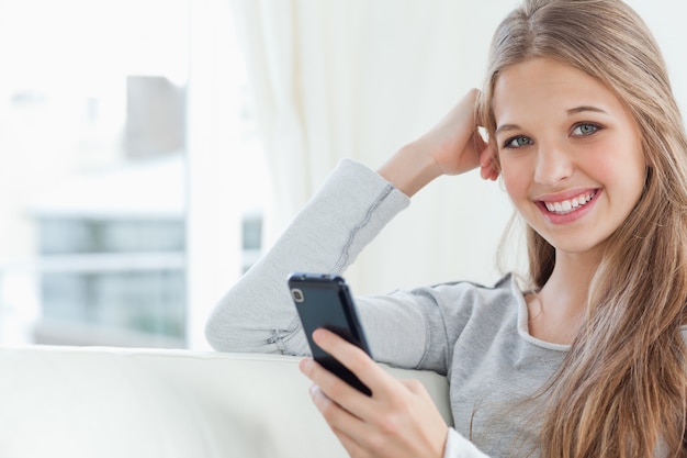 Um, menina sorridente, com, um, telefone, em, mão, como, ela, olha, a, câmera