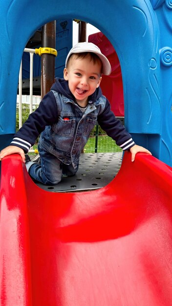 Um menino a brincar num escorregador vermelho e azul