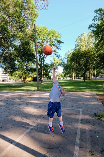 Foto um menino a jogar basquetebol no parque.