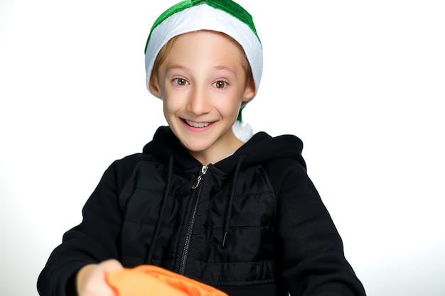 Um menino alegre com um chapéu de Papai Noel verde segura uma bolsa amarela