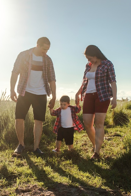 Foto um menino andando de mãos dadas com seus pais na campina