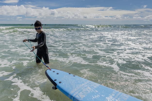 Um menino ansiosamente vestindo um maiô e óculos está praticando surf