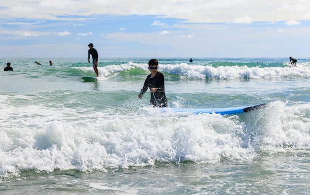 Um menino ansiosamente vestindo um maiô e óculos está praticando surf