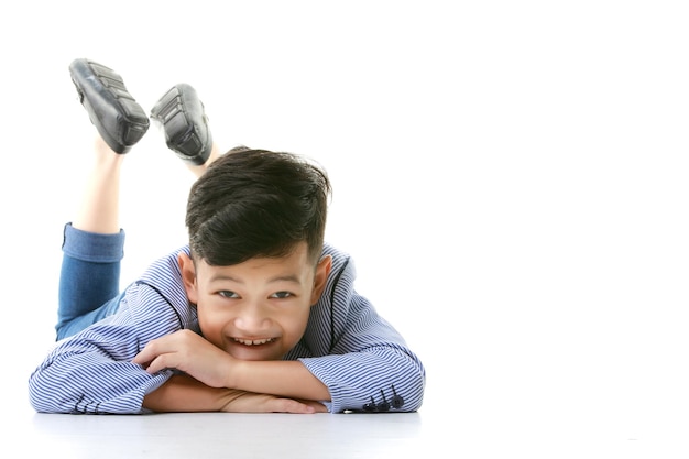 Um menino asiático de 10 anos em uma jaqueta casual está deitado no chão e sorrindo alegremente de bom humor olhando para a câmera Conceitos positivos para crianças e estilos de vida de homens jovens