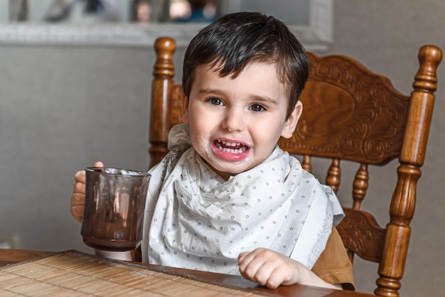 Um menino bebe de uma caneca sozinho