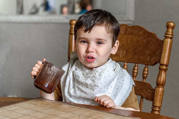 Um menino bebe de uma caneca sozinho