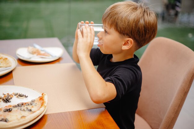 Um menino bebendo água em uma mesa