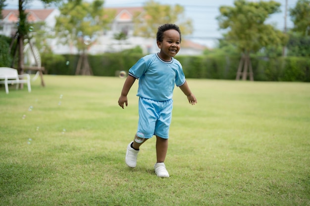 Um menino bonitinho brincando com bolhas de sabão no parque em um dia claro